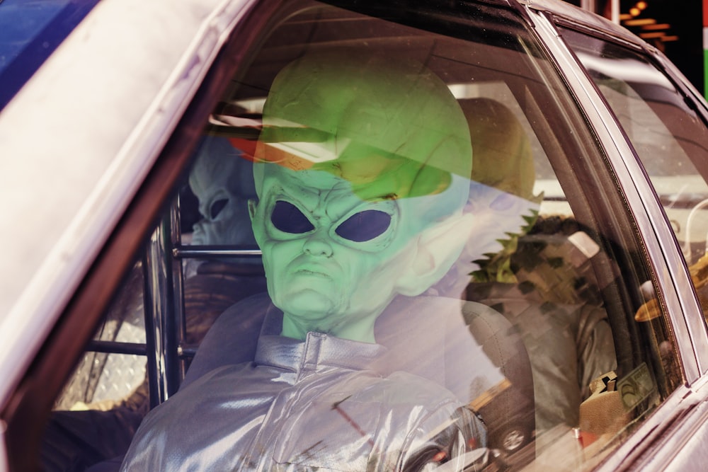 uomo in maschera verde all'interno dell'auto