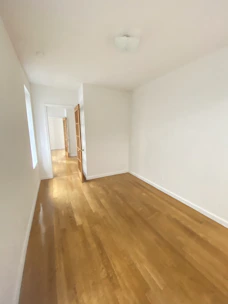 Empty, light-filled interior of a contemporary property with wooden flooring.