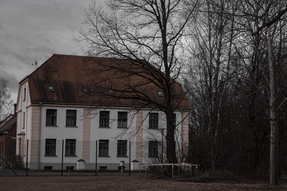 brown and white concrete building near bare trees under white clouds during daytime