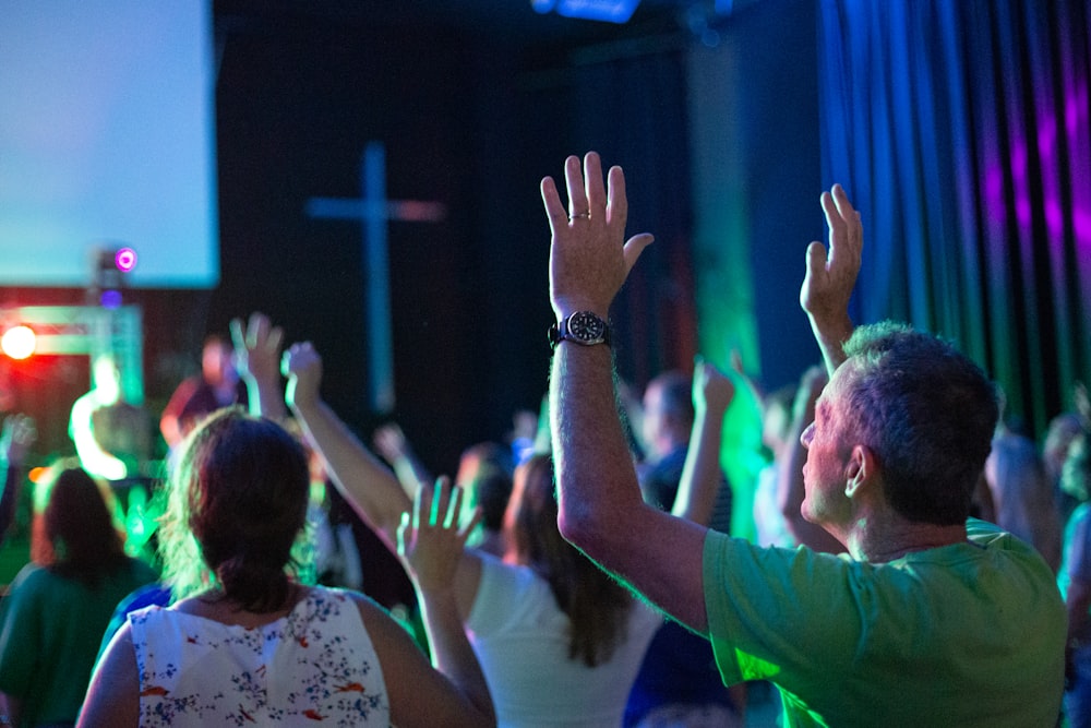 man in green shirt raising his hands