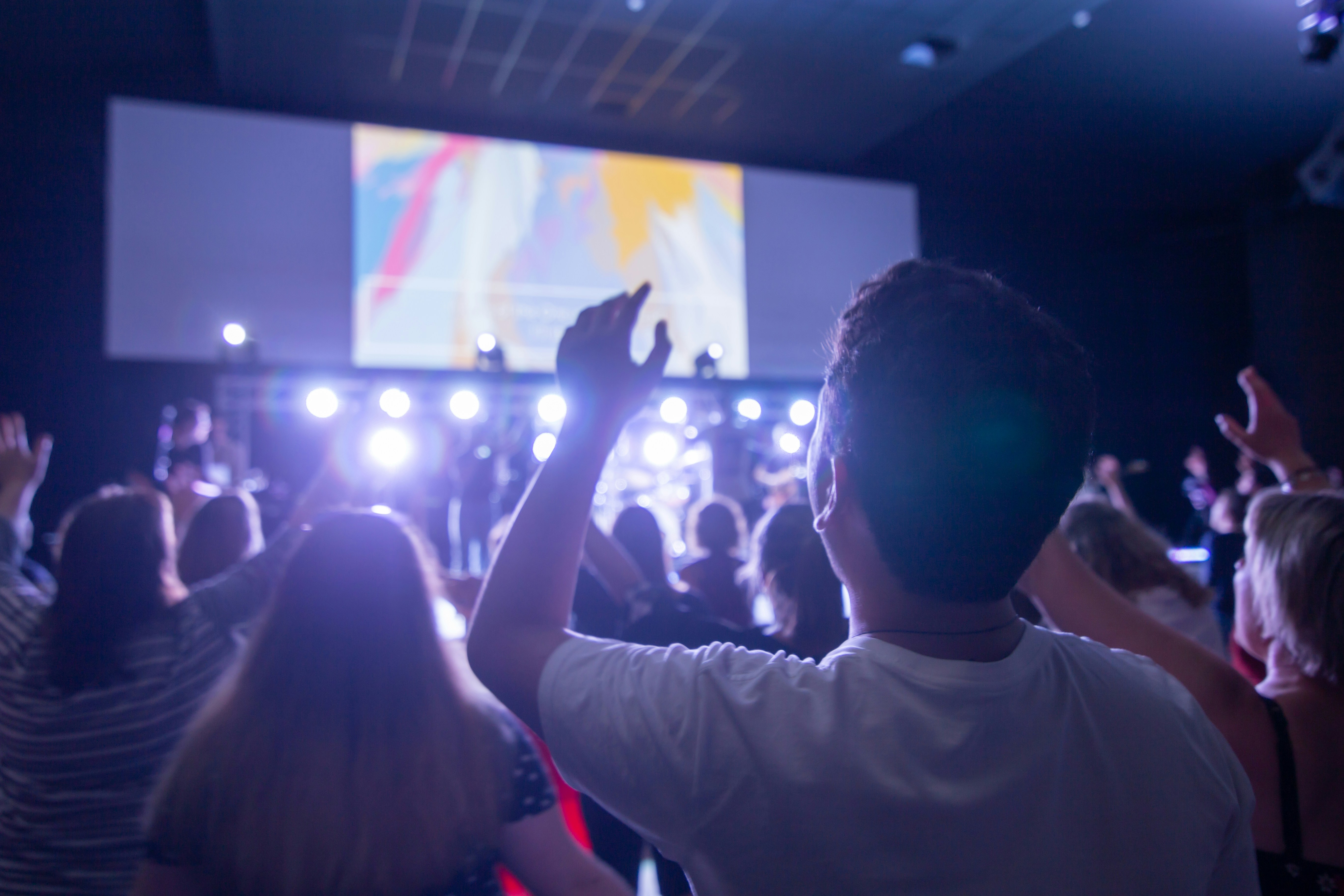 man in white shirt raising his hands