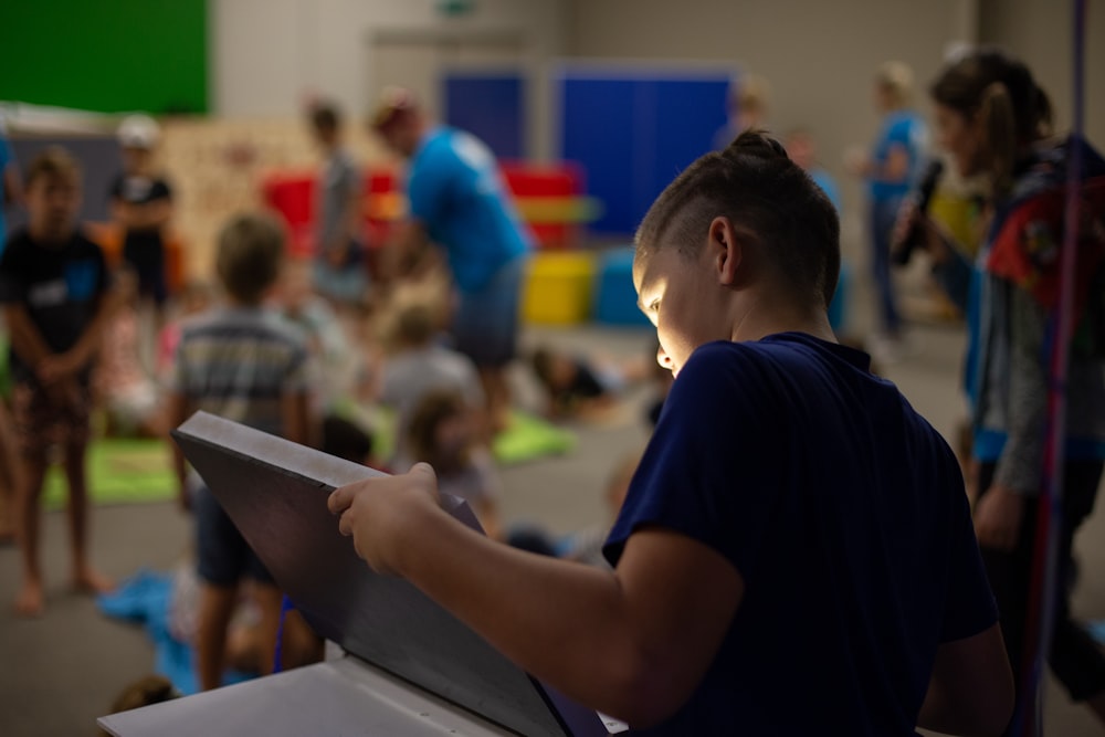 boy in black t-shirt holding tablet computer