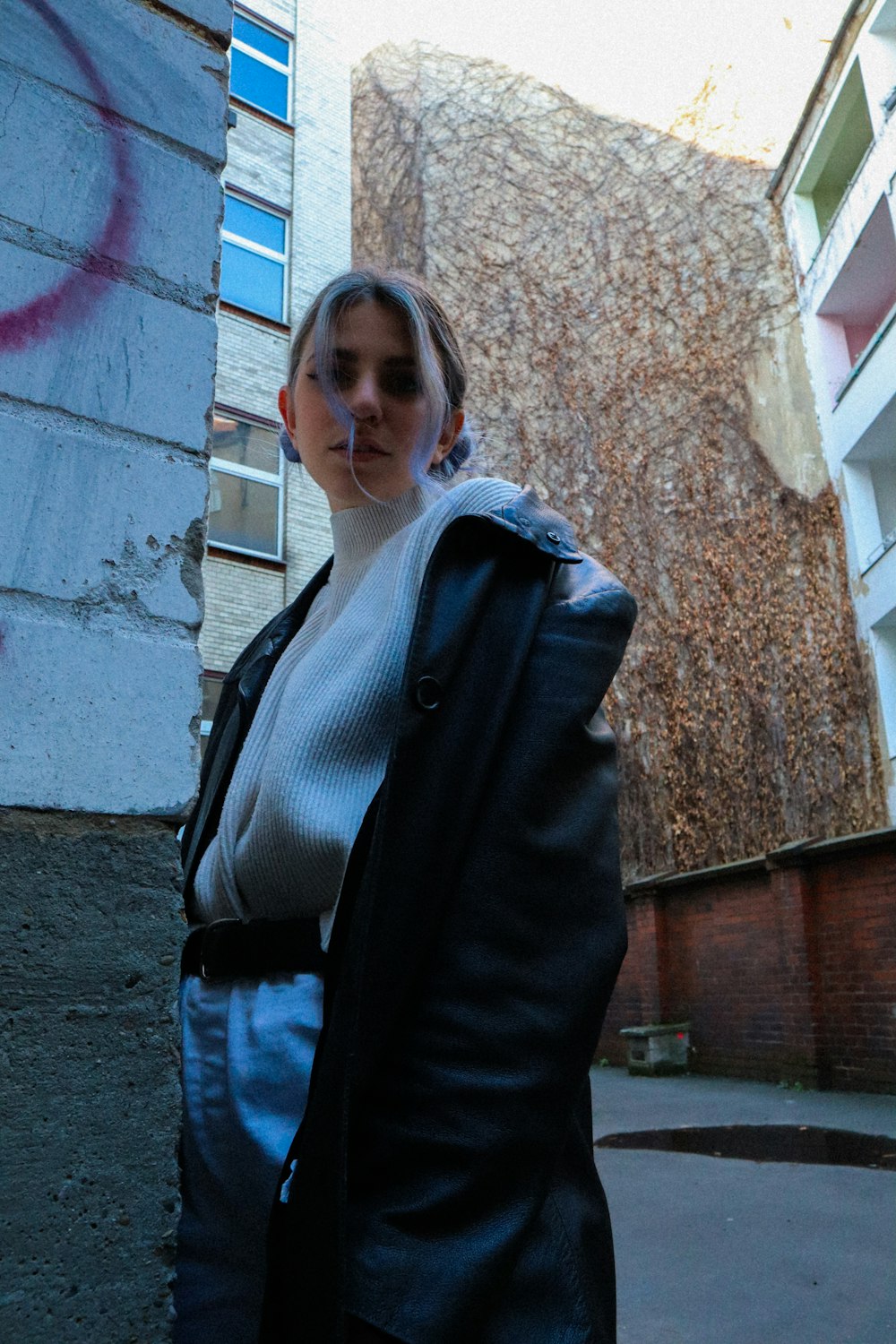 woman in black blazer standing near brown brick wall during daytime