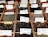 A variety of loose leaf teas displayed in wooden boxes, each with labels indicating different flavors and blends such as Té Verde Mediterraneo, Pu-Erh, and Té Pakistani. The teas have a range of colors and ingredients, with some featuring flower petals and spices. Metal scoops are visible in some of the boxes for serving.