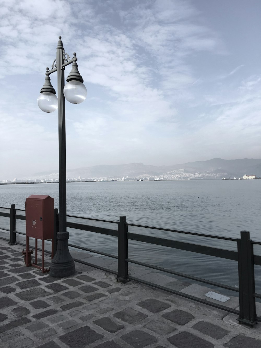 black and white street lamp near body of water during daytime