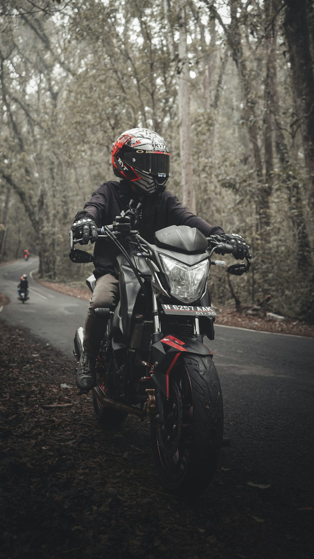 昼間の道路でバイクに乗る黒いオートバイスーツの男