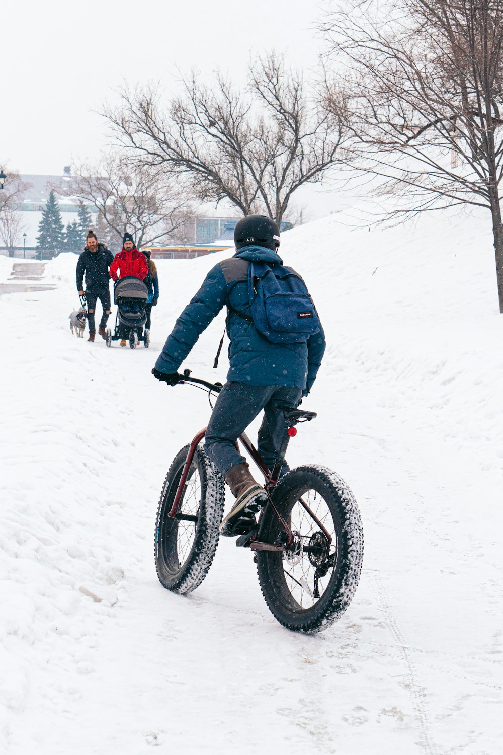 Mann in blauer Jacke fährt tagsüber auf schwarzem BMX-Bike auf schneebedecktem Untergrund