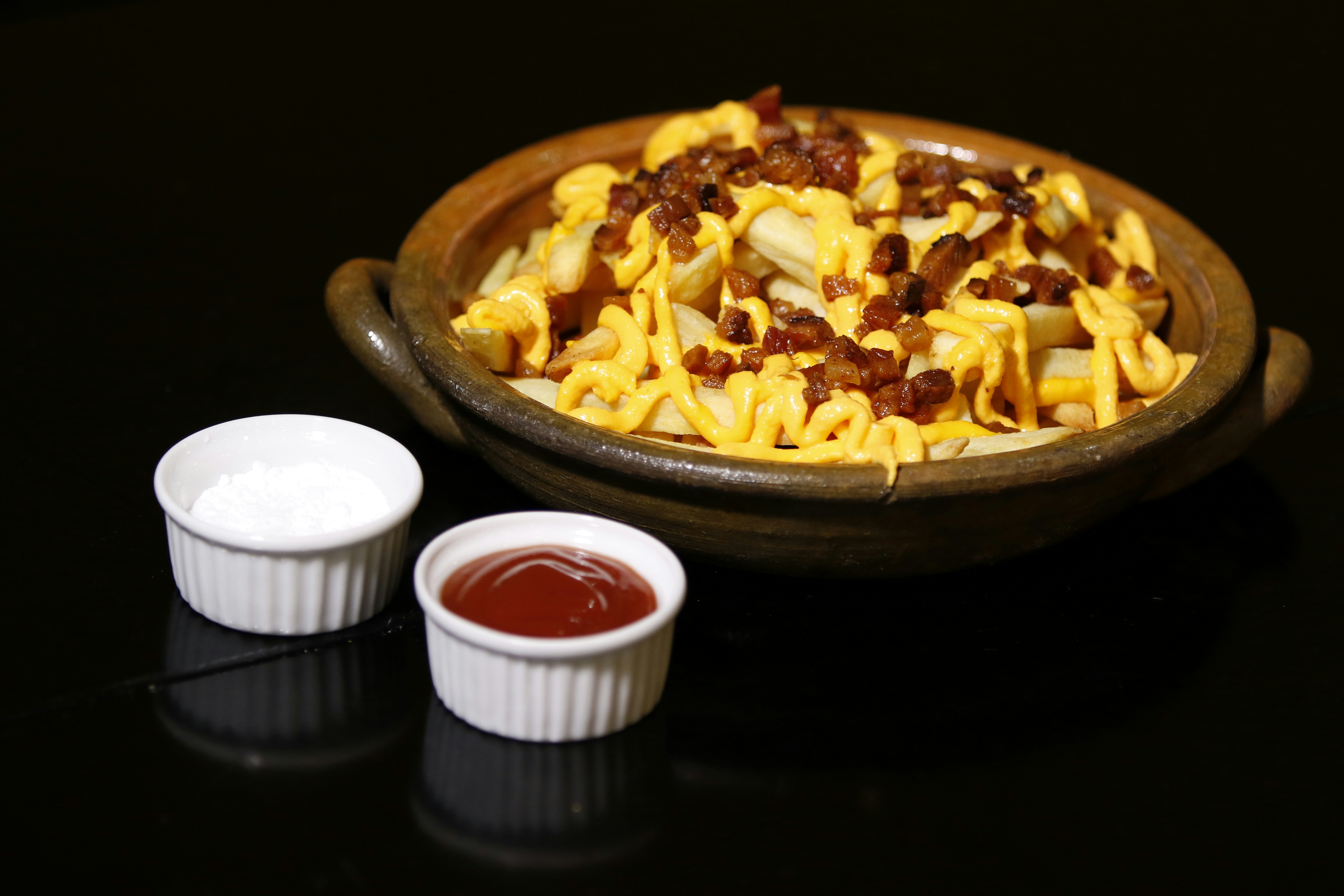 Bowl of nachos with cheese and chilli beside dips