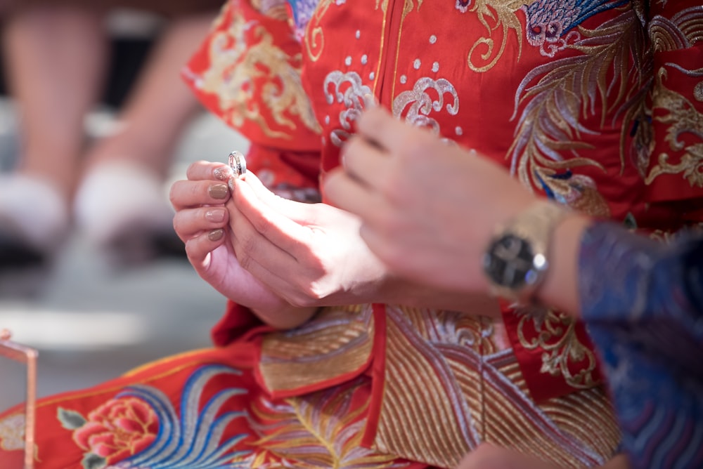 persona in camicia a maniche lunghe floreale rossa e marrone che tiene una tazza di ceramica bianca