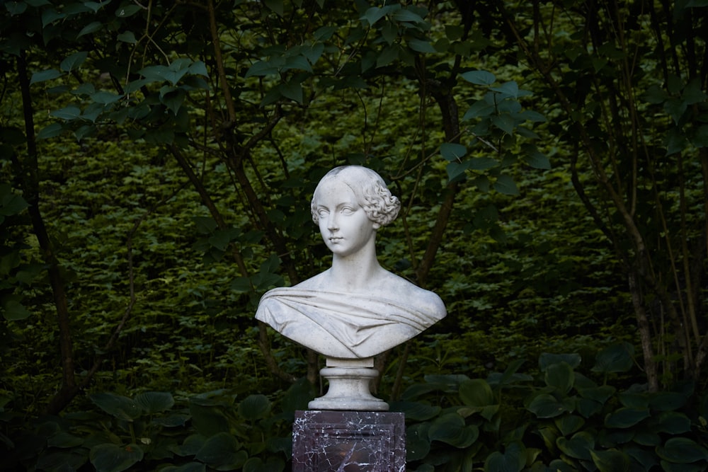 white concrete statue near green leaves