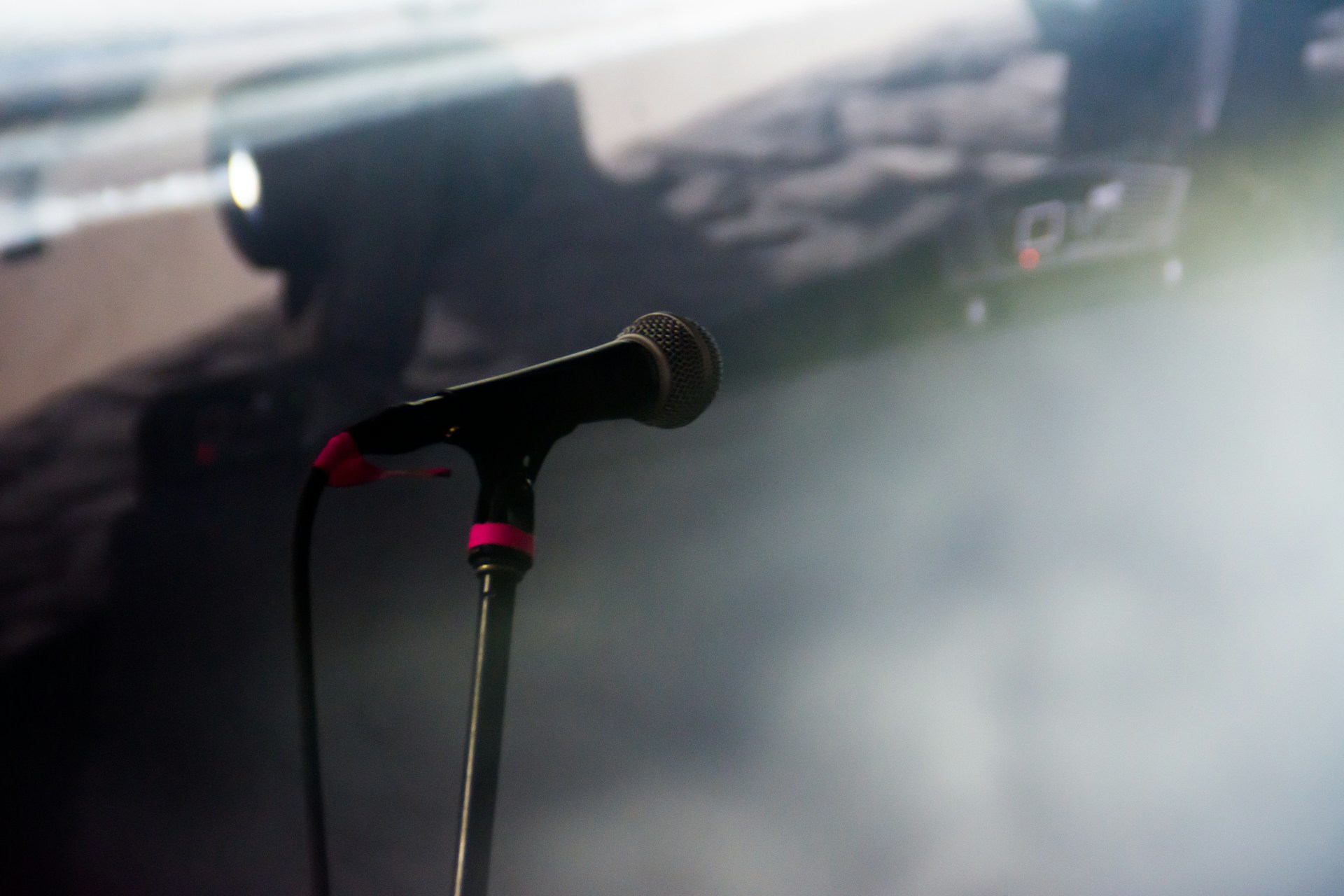 Behind-the-scenes moment of Uday preparing for a show, adjusting a microphone with soft stage lights glowing in the background.