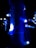 A series of vibrant blue LED lights are wrapped around a vertical pole, casting a strong glow in the dark surroundings. Additional lights can be seen in the background, creating a festive atmosphere.