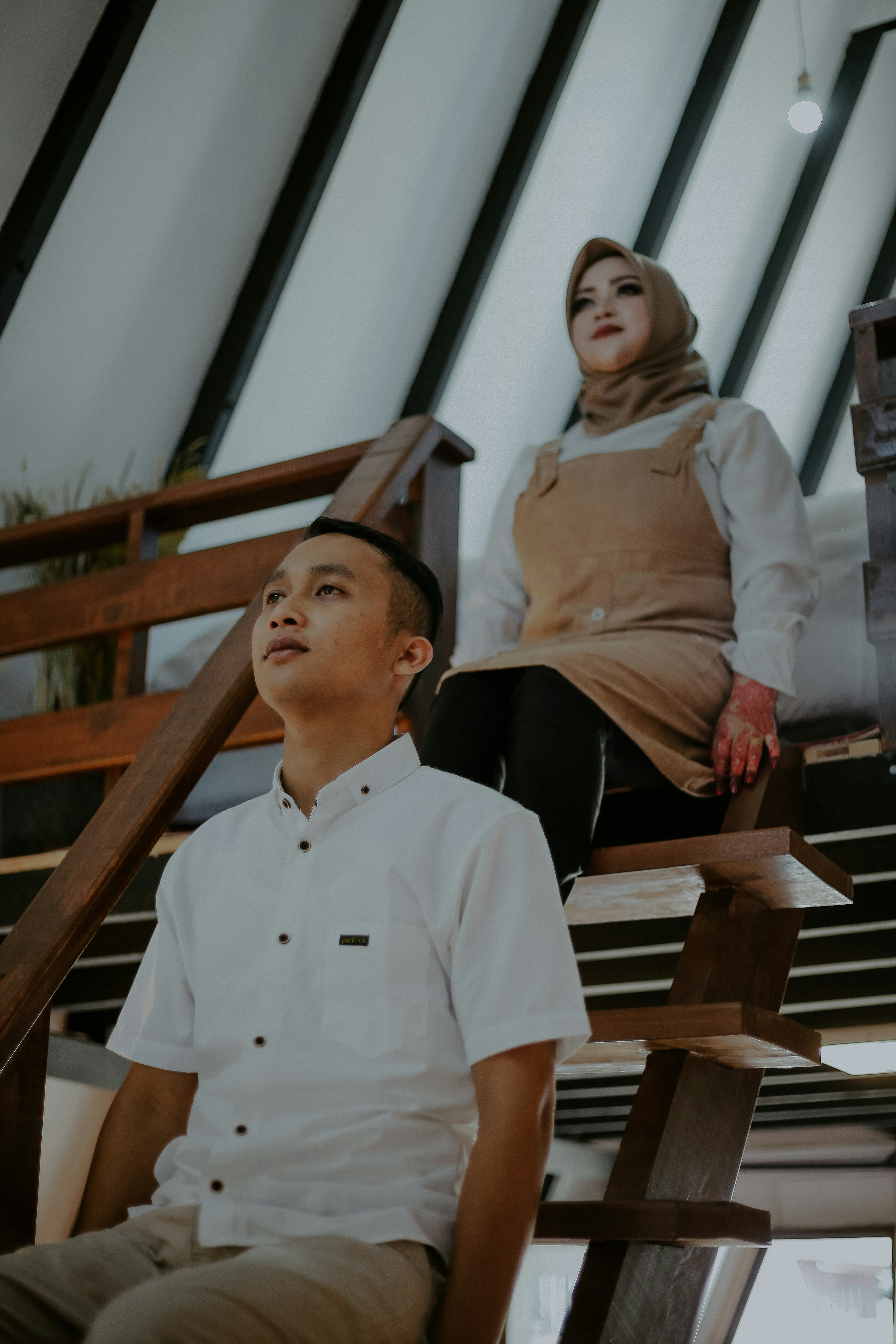 Pria berbaju putih duduk di bangku kayu coklat