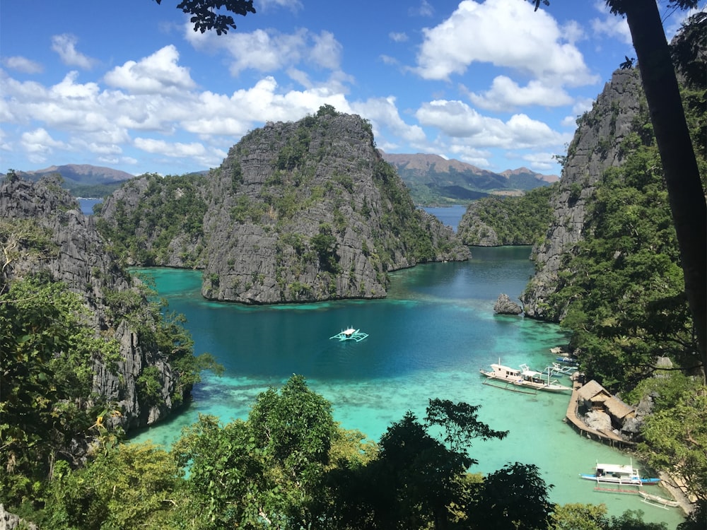 green lake surrounded by green trees and mountains under blue sky and white clouds during daytime