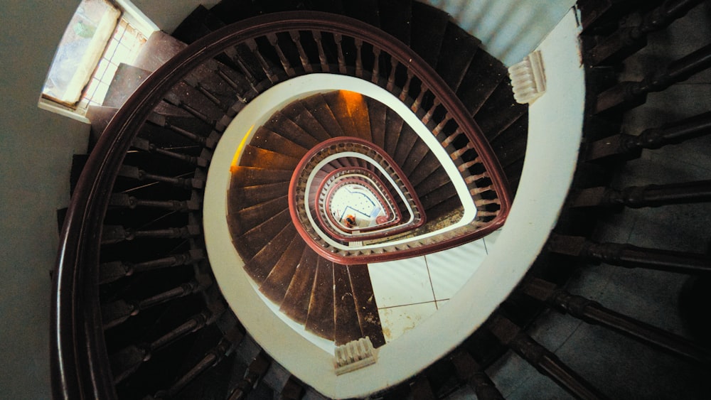 Escalera de caracol marrón con barandillas de madera marrón