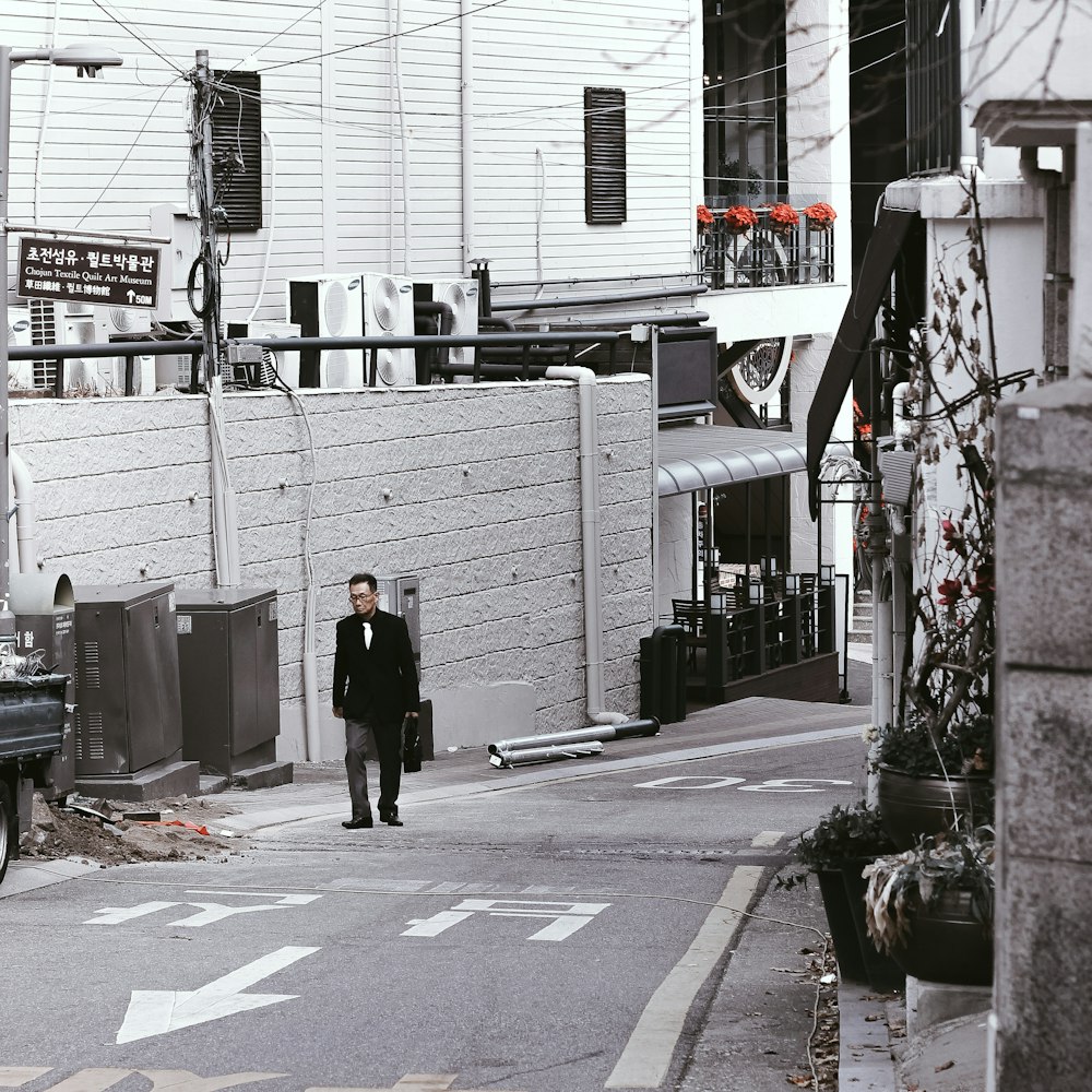 man in black jacket walking on sidewalk during daytime