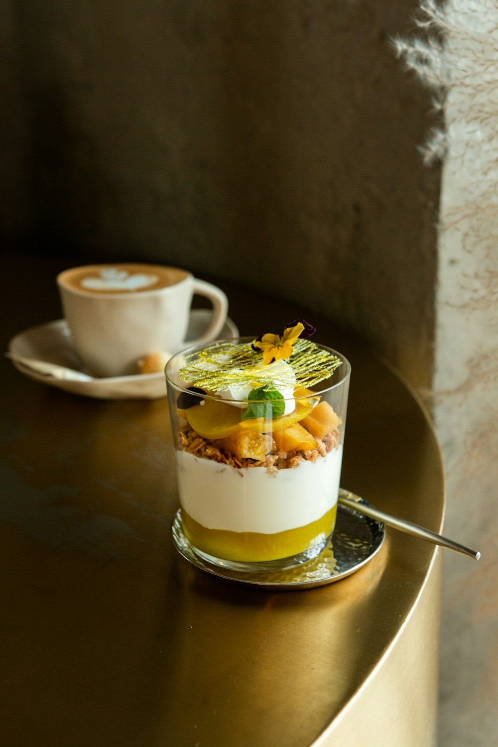 茶色の木製のテーブルに白いクリームと黄色と緑の葉が付いた透明なコップ