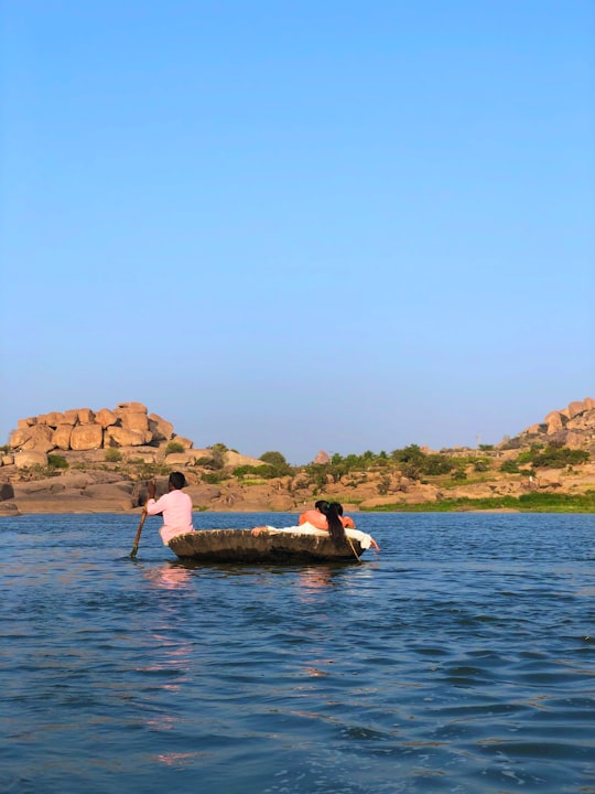 man in white shirt riding on boat on water during daytime in Hampi India