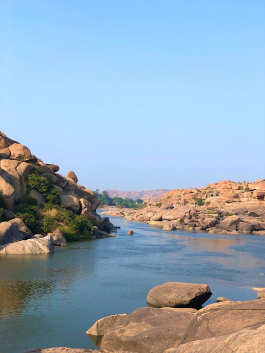 brown rocky mountain beside blue sea under blue sky during daytime in Hampi India