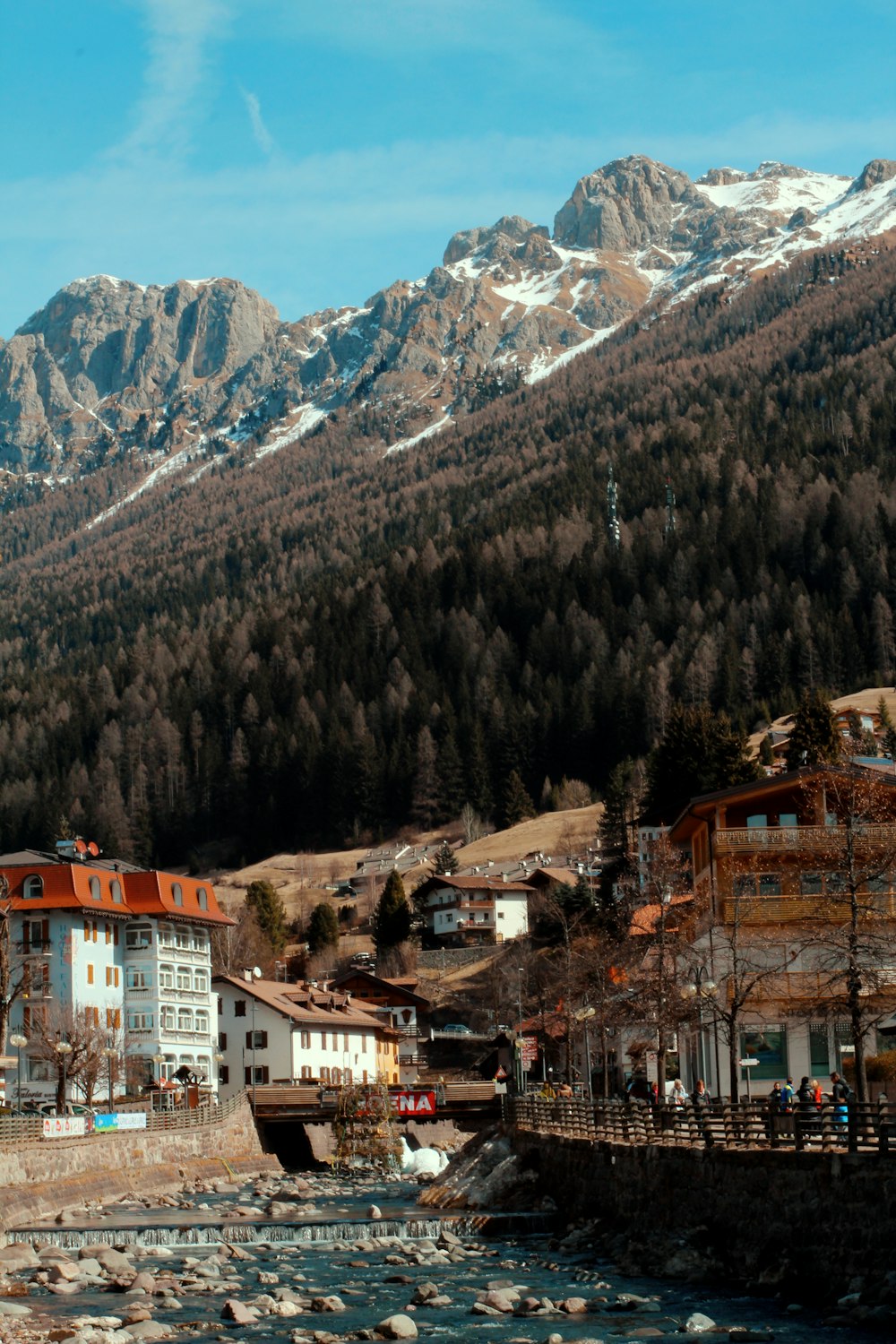 white and brown concrete buildings near green trees and mountain during daytime