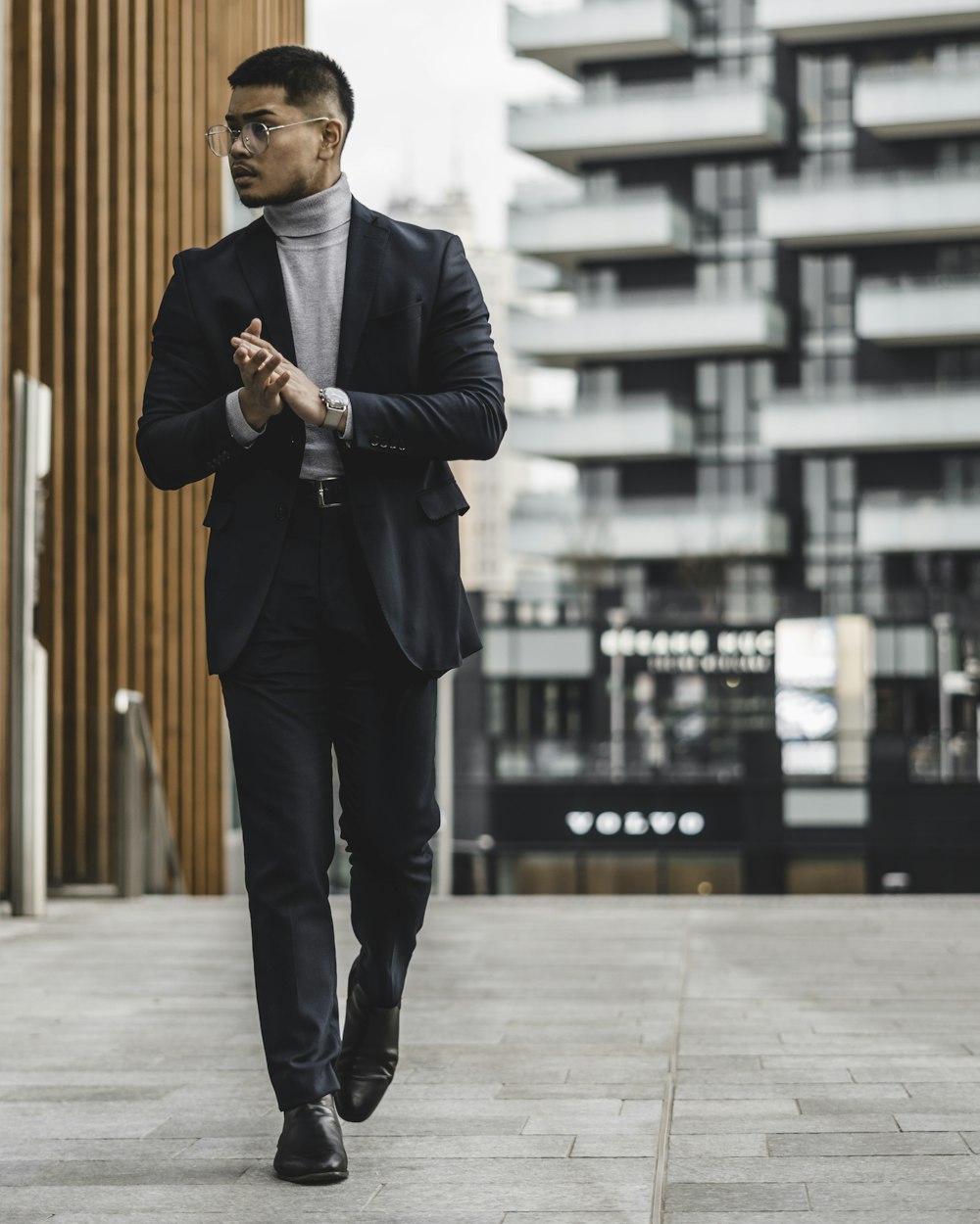 man in black suit standing on sidewalk during daytime