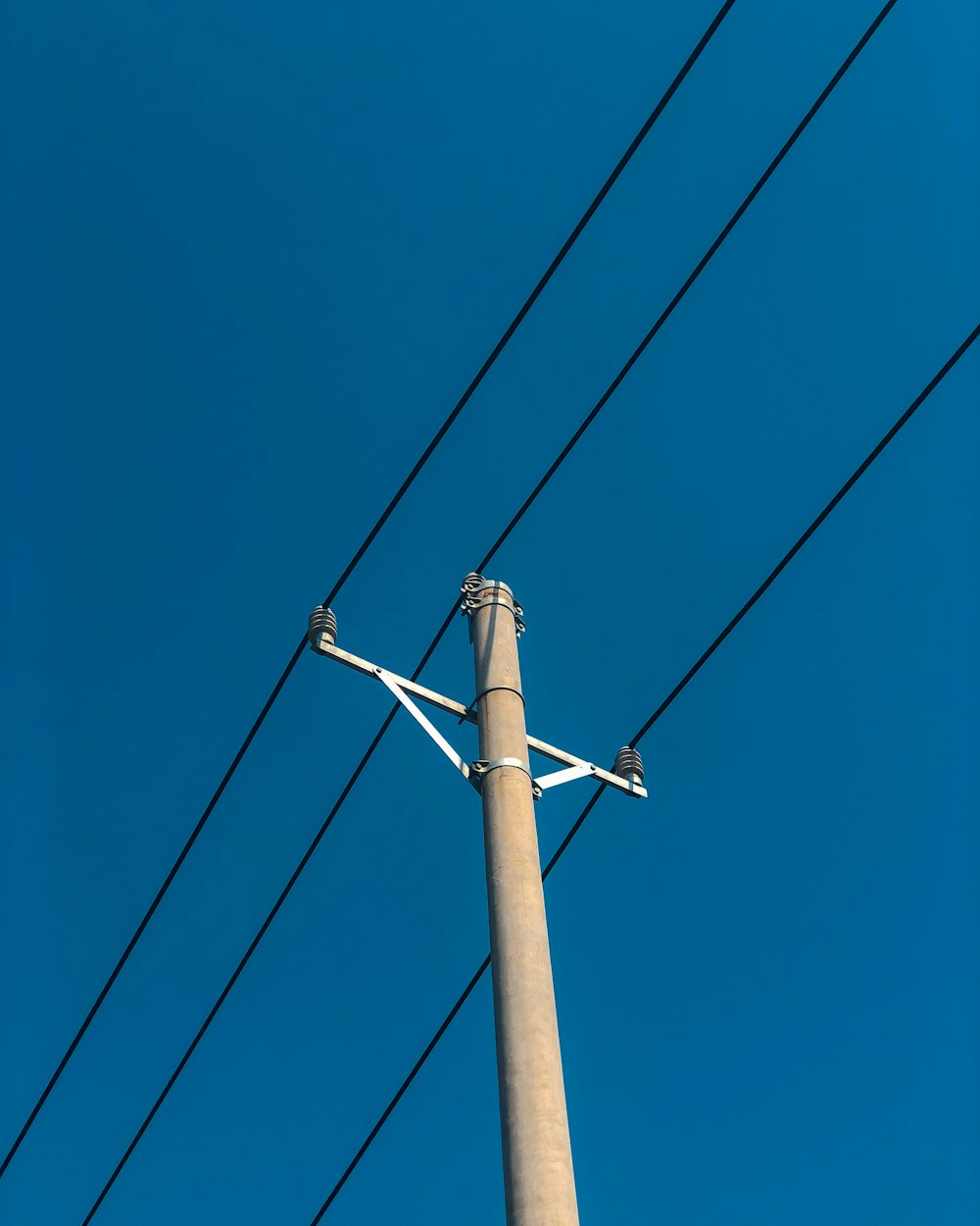 낮 동안 푸른 하늘 아래 갈색 전기 포스트