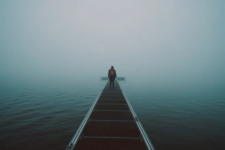 woman in black shirt and black pants standing on brown wooden dock