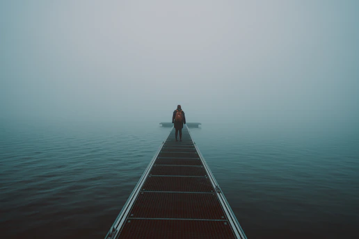 woman in black shirt and black pants standing on brown wooden dock