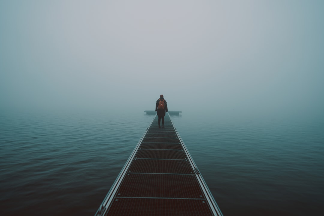 woman in black shirt and black pants standing on brown wooden dock