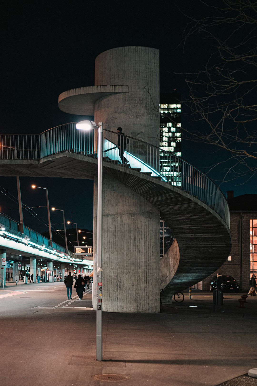 people walking on sidewalk near lighted bridge during night time