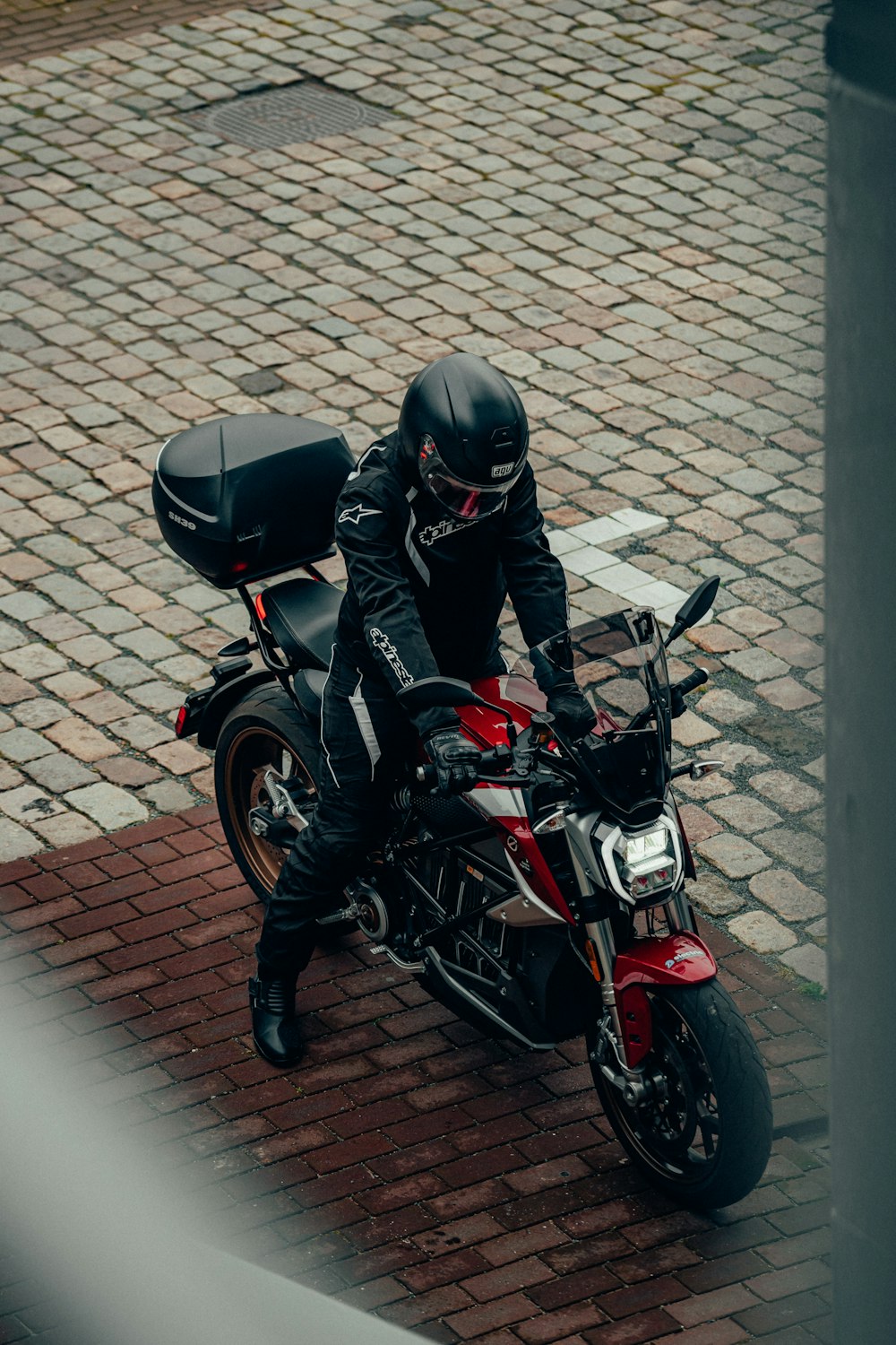 man in black leather jacket and black helmet riding red and black motorcycle