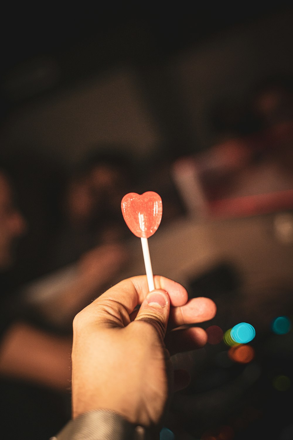 person holding red heart lollipop
