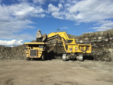 yellow and black heavy equipment on brown sand under blue sky during daytime