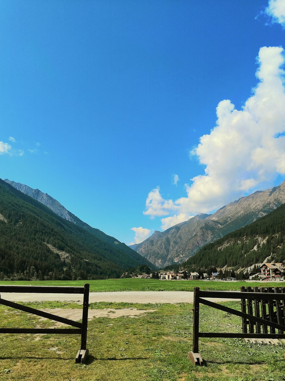 green grass field near green mountains under blue sky during daytime