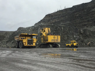 Workers coordinating the loading of heavy mining equipment onto transport vehicles.