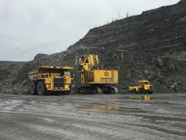 Workers coordinating the loading of heavy mining equipment onto transport vehicles.