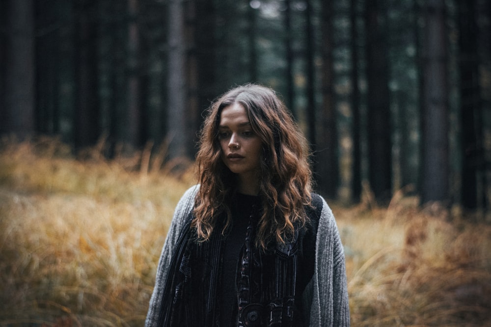 woman in black jacket standing in forest during daytime