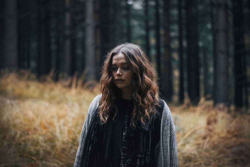 donna in giacca nera in piedi nella foresta durante il giorno