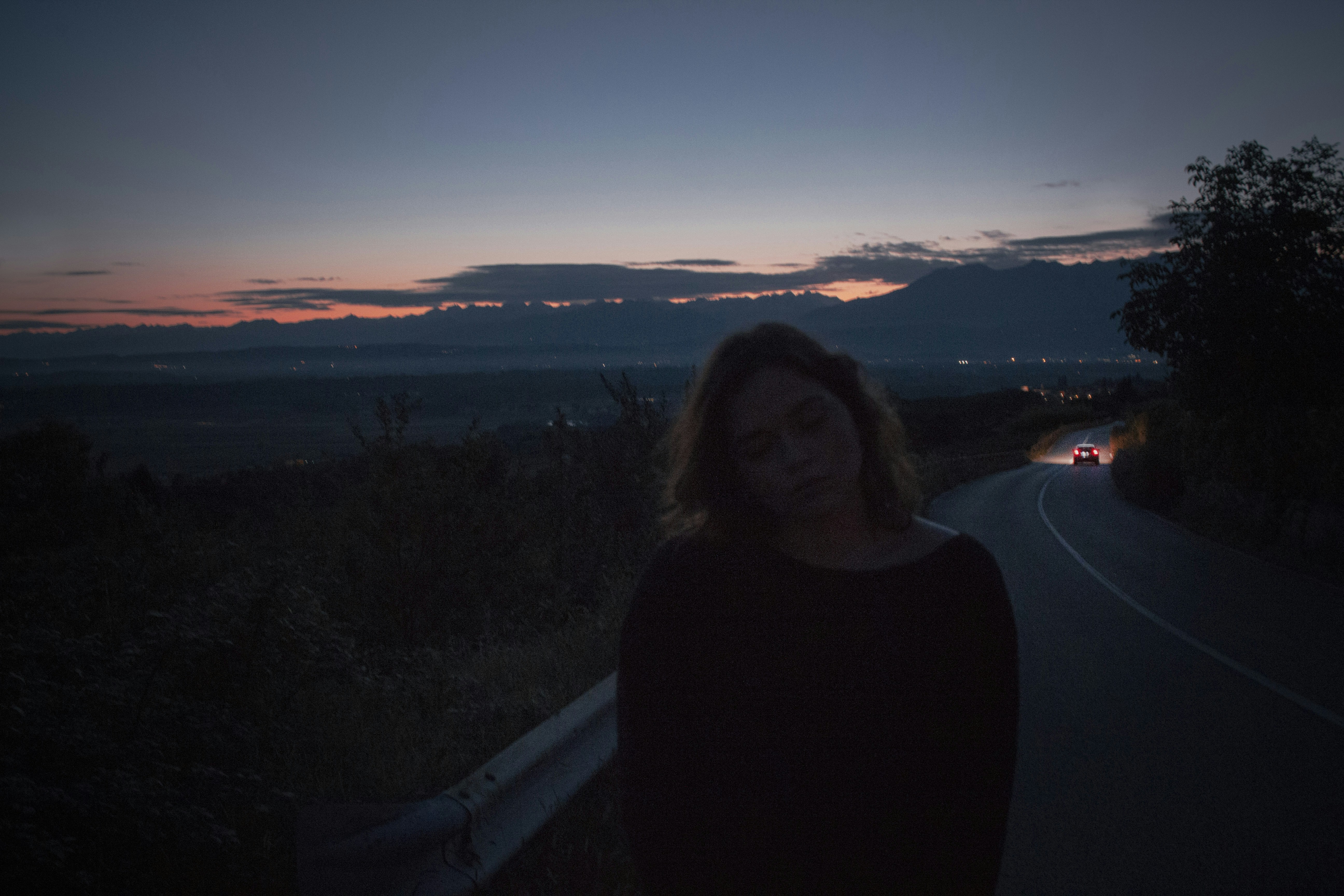 woman in black turtleneck sweater standing on top of mountain during sunset