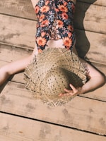Sunlight filtering through palm leaves onto a coral-colored one-piece swimsuit laid out on a wooden deck.