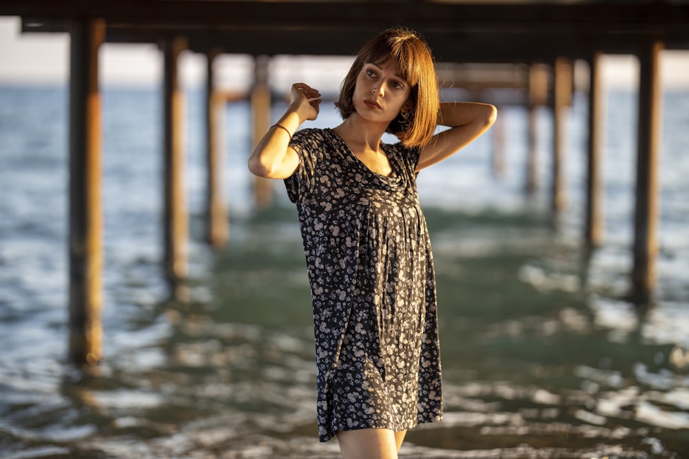 woman in black and white floral dress standing on beach during daytime