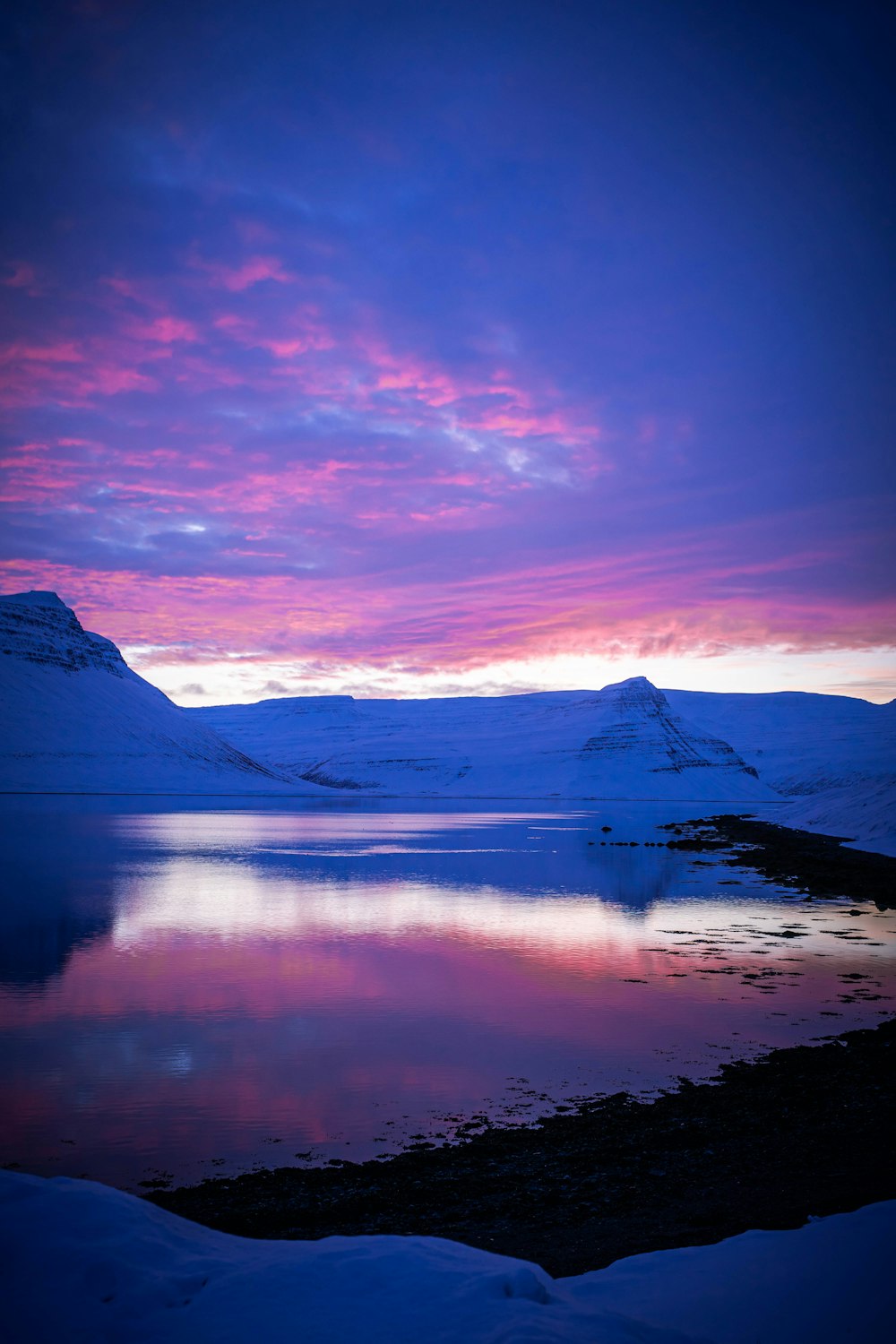 body of water near mountain under blue sky during daytime