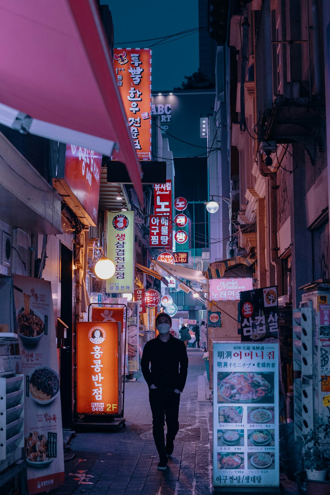 man in black jacket walking on street during nighttime