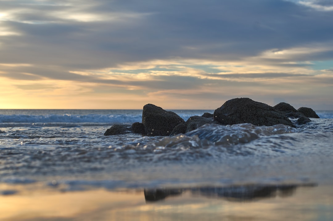 black rock formation on sea during sunset