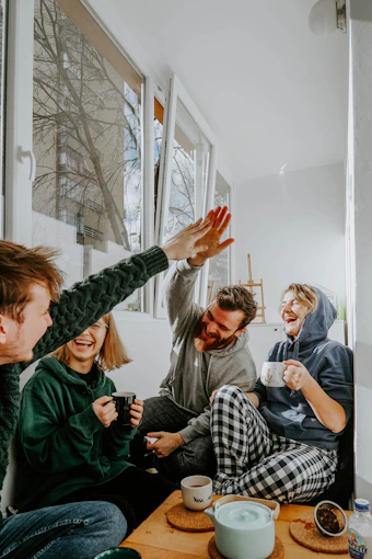 four friends laughing and high fiving over coffee