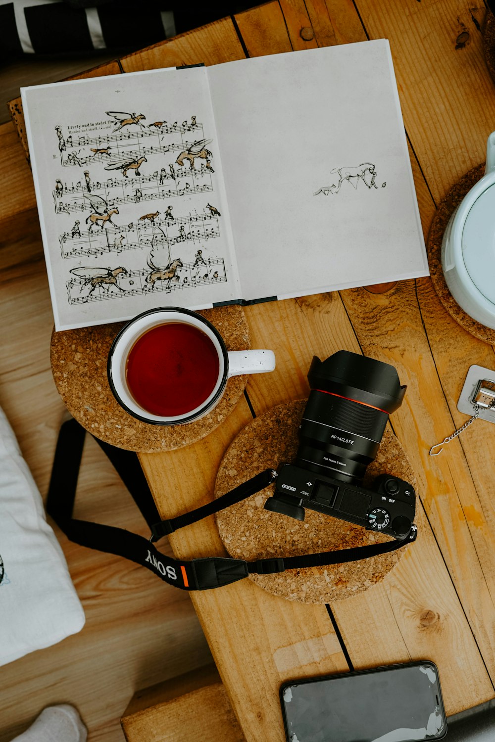 black dslr camera beside white ceramic mug on brown wooden table