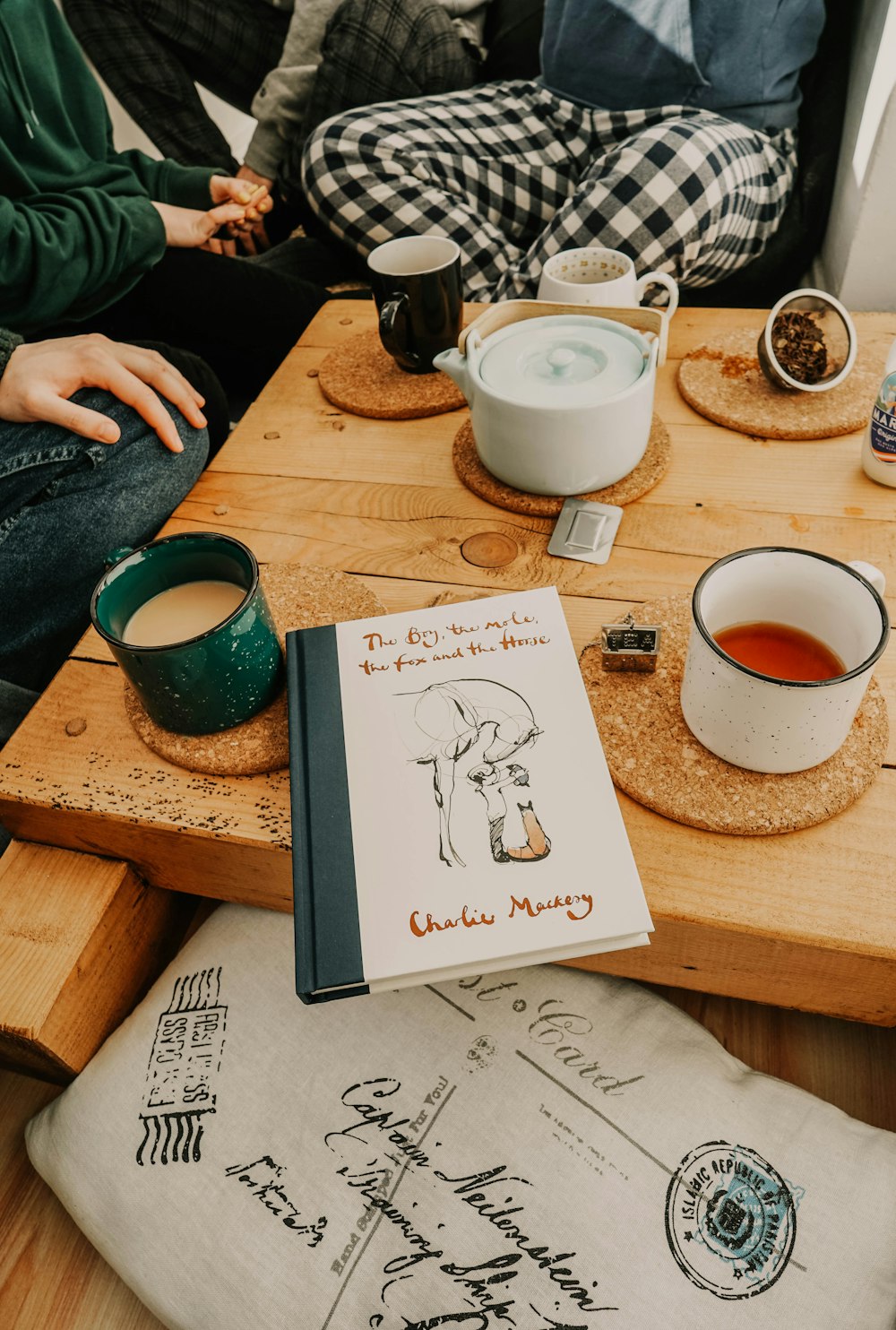 person writing on white paper beside white ceramic mug on brown wooden table