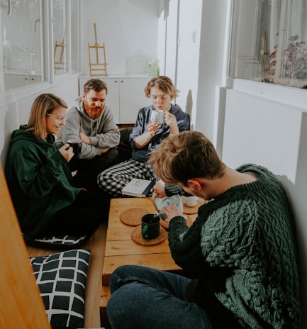 A small group of friends chatting warmly over coffee at a window seat with soft natural light.