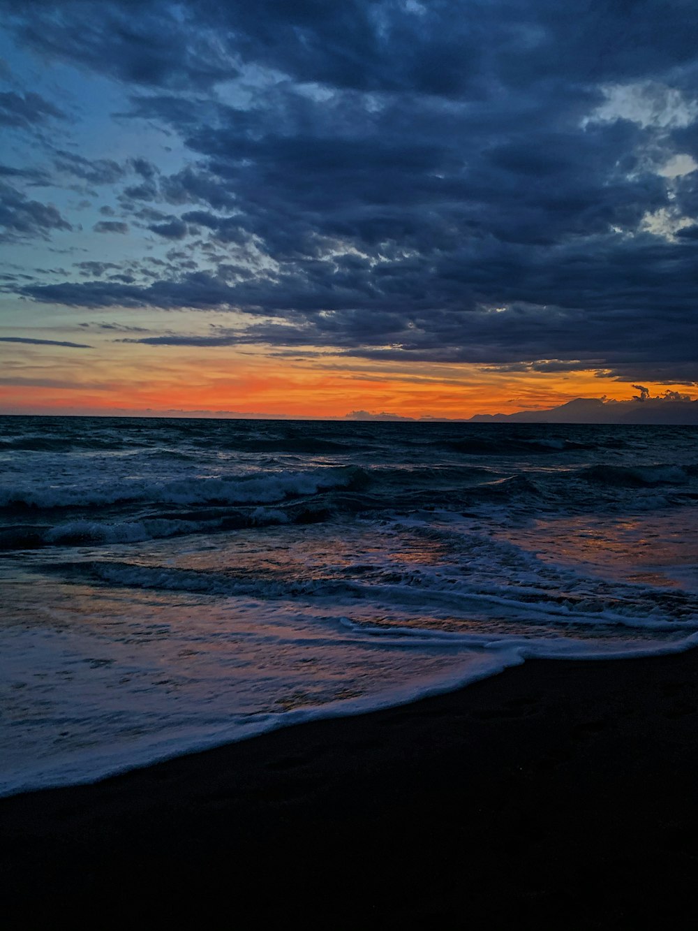 ocean waves crashing on shore during sunset