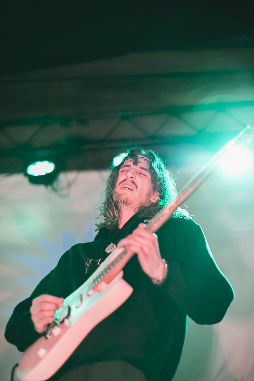 man in black long sleeve shirt holding white electric guitar